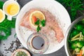 Whole raw organic fish sea perch on ice cubes in white plate on a dark table background with black pepper, olive oil, dill, cilant Royalty Free Stock Photo