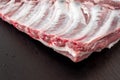 Whole raw pork ribs isolated on dark, black, stone board. spare ribs or belly. close-up Royalty Free Stock Photo