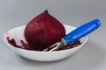 Raw peeled red beetroot and peeler among peelings in bowl