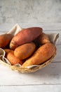Whole raw sweet potatoes in a basket, on bright background, top view. Royalty Free Stock Photo