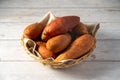 Whole raw sweet potatoes in a basket, on bright background. Royalty Free Stock Photo