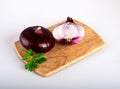 A whole red flat onion and half an onion with parsley leaves on a cutting Board, isolated on a white background