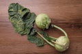 Whole ripe kohlrabies with leaves on wooden table, flat lay