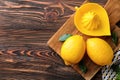 Whole ripe lemons and juicer on wooden table