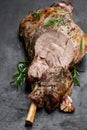 Whole roast lamb leg on black stone background