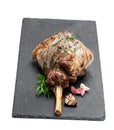 Whole roast lamb leg on black stone background