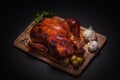 Whole roasted chicken on cutting board with vegetables over black background Royalty Free Stock Photo
