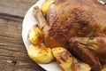 Whole roasted chicken with potatoes on rustic wooden table. Sele