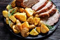 Whole roasted pork loin with baked potato wedges Royalty Free Stock Photo