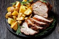 Whole roasted pork loin with baked potato wedges Royalty Free Stock Photo