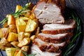 Whole roasted pork loin with baked potato wedges Royalty Free Stock Photo