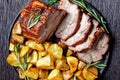 Whole roasted pork loin with baked potato wedges Royalty Free Stock Photo