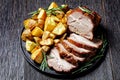 Whole roasted pork loin with baked potato wedges Royalty Free Stock Photo