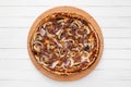 Whole round pizza on wooden plate topped with mushrooms, onion and chopped meat. Top view on white board background Royalty Free Stock Photo