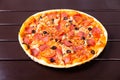 A whole rustic pizza with mozzarella, salami, tomato, olives, mushrooms and basil Royalty Free Stock Photo