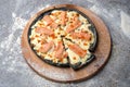 Seafood black dough Pizza with salmon slices, mozzarella cheese and red caviar on wooden board