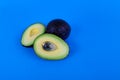 Whole and sliced avocados pit showing on blue background