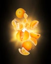 Whole and sliced fresh oranges in the air with flash of light in the dark Royalty Free Stock Photo