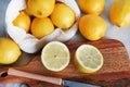 Whole and sliced lemons on a wooden board next to a knife Royalty Free Stock Photo