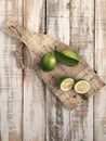 Whole and sliced limes on a wooden cutting board on table Royalty Free Stock Photo