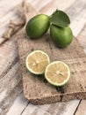 Whole and sliced limes on a wooden cutting board on table Royalty Free Stock Photo