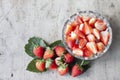 Whole and sliced piece strawberry fruit in bowl on brown wooden table.