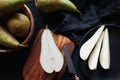 Whole and sliced ??ripe pears on a wooden board and plates on a dark background Royalty Free Stock Photo