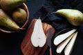 Whole and sliced ??ripe pears on a wooden board and plates on a dark background Royalty Free Stock Photo