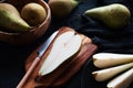 Whole and sliced ??ripe pears on a wooden board and plates on a dark background Royalty Free Stock Photo