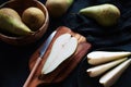 Whole and sliced ??ripe pears on a wooden board and plates on a dark background Royalty Free Stock Photo