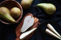 Whole and sliced ??ripe pears on a wooden board and plates on a dark background Royalty Free Stock Photo