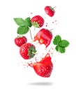 Whole and sliced strawberries with juice splashes in the air isolated on a white background Royalty Free Stock Photo