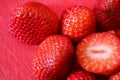 Whole and sliced strawberries on red cutting board background - selective focus - very red Royalty Free Stock Photo