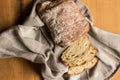 Whole sourdough bread loaf on kitchen cloth on rustic wooden table - top view