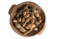 Whole tamarind fruits in round wooden bowl