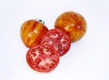 Whole tomatoes and a halves cut tomatoes on a white background. Ripe motley tomatoes. Royalty Free Stock Photo