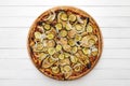 Whole vegetarian pizza topped with grilled eggplant, zucchini and onion, on wooden plate. Top view on white board