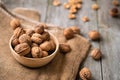 Whole walnuts in a bowl and jute bag on rustic old wooden table.