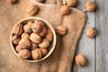 Whole walnuts in a bowl and jute bag on rustic old wooden table.