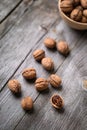 Whole walnuts in a bowl and on rustic old wooden table.