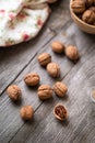 Whole walnuts in a bowl and on rustic old wooden table.