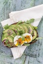 Whole wheat bread Avocado, poached egg sandwich with fresh herbs,red onion on dishcloth wooden board background. Healthy Royalty Free Stock Photo