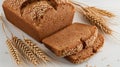 Whole wheat bread loaf paired with wheat stalks on a clean white backdrop Royalty Free Stock Photo