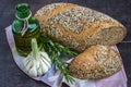 Whole wheat bread and rye, sprinkled with sunflower seeds, poppy seeds, sesame seeds, next to a bottle of olive oil, rosemary and