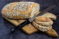 Whole wheat bread and rye, sprinkled with sunflower seeds, poppy seeds, sesame seeds, sliced with a knife on a board