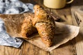 Whole wheat croissants with sesame seeds on wood kitchen table, towel, enamel mug Royalty Free Stock Photo