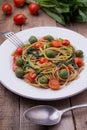 Whole wheat spaghetti with ramsons, tomatoes and olives on wood table Royalty Free Stock Photo
