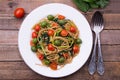 Whole wheat spaghetti with ramsons, tomatoes and olives on wood table Royalty Free Stock Photo