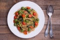 Whole wheat spaghetti with ramsons, tomatoes and olives on wood table Royalty Free Stock Photo