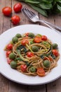 Whole wheat spaghetti with ramsons, tomatoes and olives on wood table Royalty Free Stock Photo